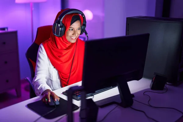 Young beautiful woman streamer playing video game using computer at gaming room