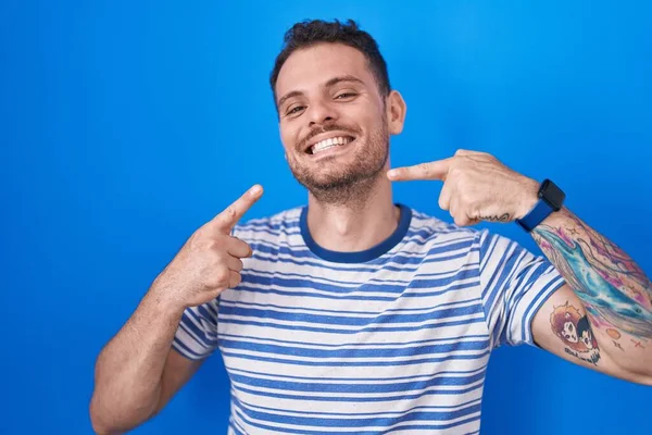 Joven Hombre Hispano Pie Sobre Fondo Azul Sonriendo Alegre Mostrando —  Fotos de Stock