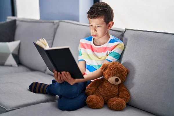 Genç Beyaz Bir Çocuk Kanepede Oturmuş Depresif Bir Kitap Okuyor — Stok fotoğraf