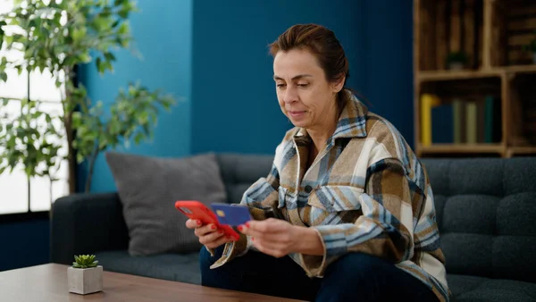 Mujer Hispana Mediana Edad Usando Teléfono Inteligente Tarjeta Crédito Sentada —  Fotos de Stock