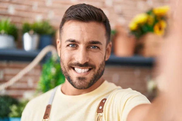 Young hispanic man florist smiling confident make selfie by camera at florist