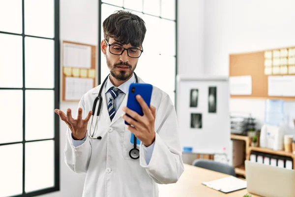 Joven Médico Hispano Con Videollamada Usando Smartphone Clínica —  Fotos de Stock