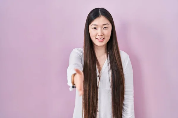 Chinese Jonge Vrouw Staan Roze Achtergrond Glimlachend Vriendelijk Aanbieden Van — Stockfoto