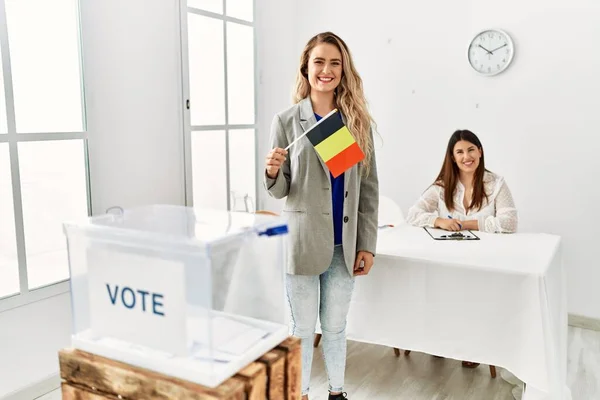 Young belgian voter woman smiling happy holding belgium flag at electoral college.