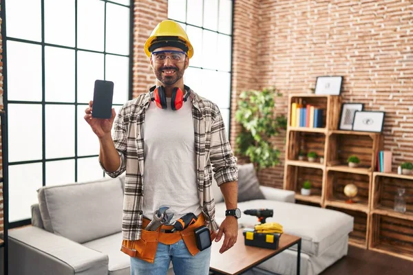 Mladý Hispánec Vousy Pracuje Doma Renovace Držení Smartphone Vypadá Pozitivně — Stock fotografie