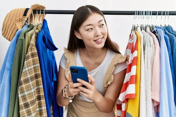 小売店でスマートフォンを使って服を探している若いアジアの女性 — ストック写真