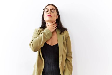Young brunette woman standing over isolated background touching painful neck, sore throat for flu, clod and infection 
