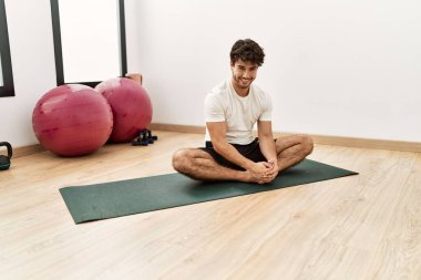 Genç İspanyol adam gülümsüyor spor merkezinde esniyor.