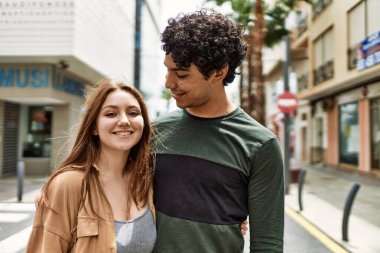 Genç, ırklar arası bir çift, gülümsüyor ve şehirde birbirlerine sarılıyorlar..