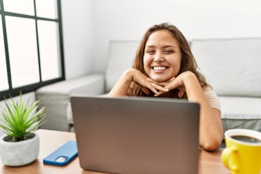 Evde dizüstü bilgisayar kullanan genç, güzel İspanyol kadın.