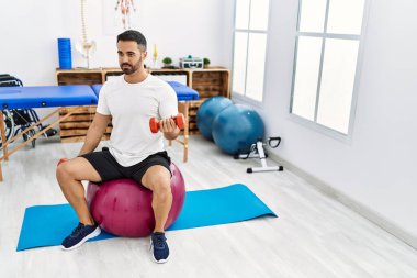 Genç İspanyol hasta rehabilitasyon seansı için klinikteki halterleri ve topları kullanıyor.