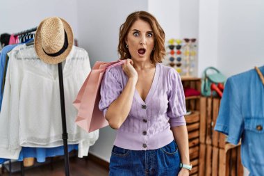 Alışveriş torbalarını elinde tutan orta yaşlı bir kadın korkmuş ve şaşırmış bir şekilde ağzı açık kalmış, inançsız bir yüz. 