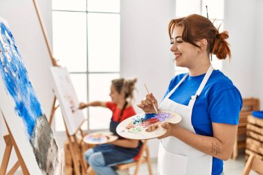 Sanat okulunda resim yaparken gülümseyen iki sanatçı öğrenci..