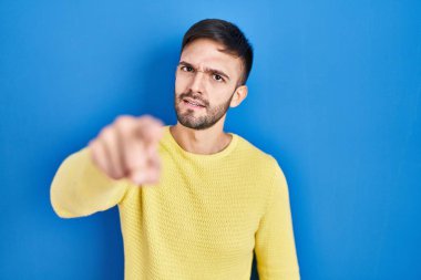 Mavi arka planda dikilen İspanyol adam kameraya kızgın ve sinirli olduğunu gösteriyor. 