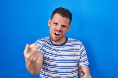 Mavi arka planda dikilen Latin asıllı genç adam kameraya kızgın ve sinirli olduğunu gösteriyor. 