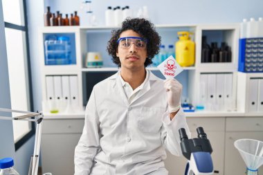 Latin asıllı, kıvırcık saçlı, bilim adamı laboratuarında çalışan zehirli afiş taşıyan, düşünceli ve ayık görünüşlü, kendine güvenen bir adam. 