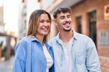 Genç adam ve kadın çift sokakta birbirlerine sarılıyorlar.