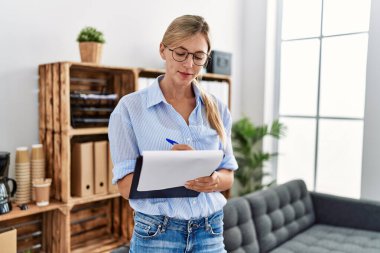 Klinikte duran panoya yazı yazan genç sarışın kadın psikolog.