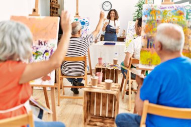 Bir grup orta yaşlı öğrenci resim stüdyosunda resim dersi alıyor..