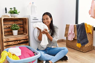 Çamaşırhanede elbise kokusu alan genç Latin bir kadın.