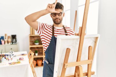 Sanat stüdyosundaki Arap genç adam parmakları alnında insanlarla dalga geçiyor. Ezik hareketler yapıyor, alay ediyor, hakaret ediyor.. 