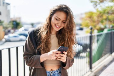 Parkta akıllı telefon kullanarak gülümseyen güzel bir İspanyol kadın.