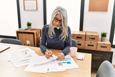 Ofiste çalışırken gülümseyen beyaz saçlı iş kadını.
