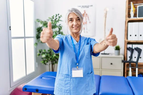 Medelålders Gråhårig Kvinna Bär Sjukgymnast Uniform Läkarmottagningen Godkänner Gör Positiv — Stockfoto