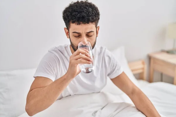 Νεαρός Άραβας Πίνει Νερό Καθισμένος Στο Κρεβάτι Στην Κρεβατοκάμαρα — Φωτογραφία Αρχείου
