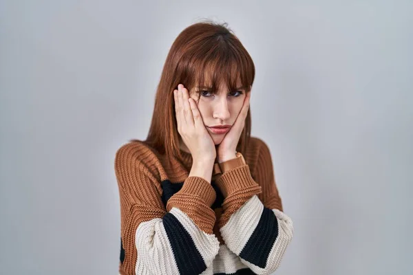 Young beautiful woman wearing striped sweater over isolated background tired hands covering face, depression and sadness, upset and irritated for problem