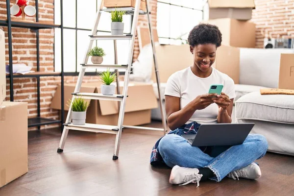 African American Woman Using Laptop Smartphone Sitting Floor New Home — стоковое фото
