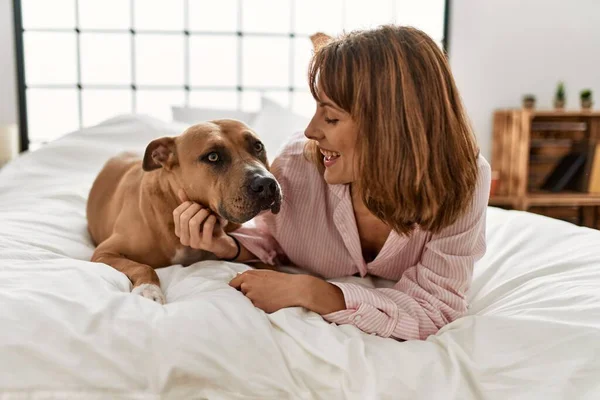 Young caucasian woman smiling confident lying on bed with dog at bedroom