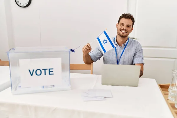 Joven Hispano Sonriendo Confiado Sosteniendo Bandera Israelel Trabajando Colegio Electoral —  Fotos de Stock