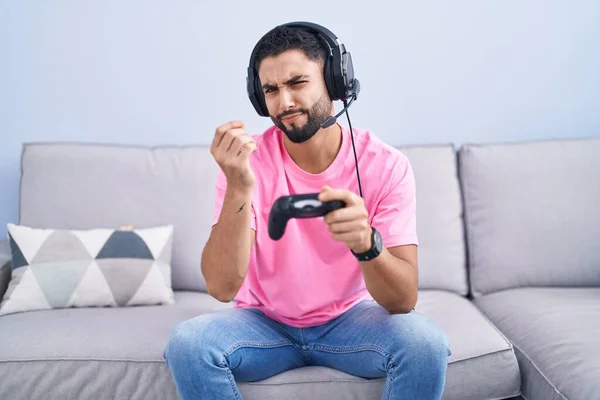 Jovem Hispânico Jogando Videogame Segurando Controlador Sentado Sofá Fazendo Gesto — Fotografia de Stock