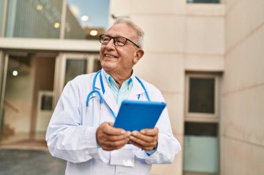 Kıdemli doktor üniforması giyiyor. Sokakta dokunmatik ped kullanıyor.