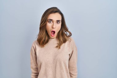 Young woman standing over isolated background afraid and shocked with surprise and amazed expression, fear and excited face. 