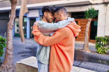 İki erkek caddede birbirlerine sarılıyorlar.