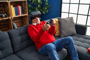 Son sınıf öğrencisi evde sanal gerçeklik gözlüğü kullanarak video oyunu oynuyor.