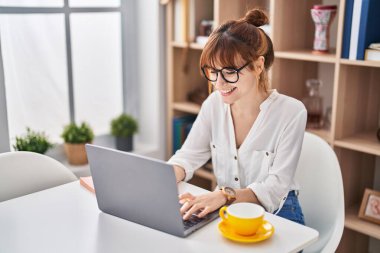 Young woman using laptop sitting on table at home