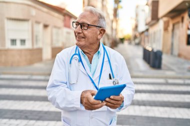 Kıdemli doktor üniforması giyiyor. Sokakta dokunmatik ped kullanıyor.