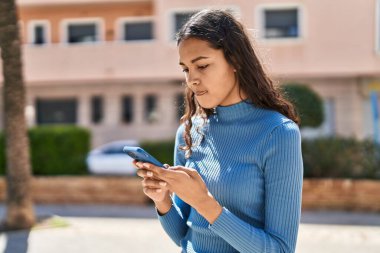 Genç Afro-Amerikan kadın parkta akıllı telefon kullanıyor.