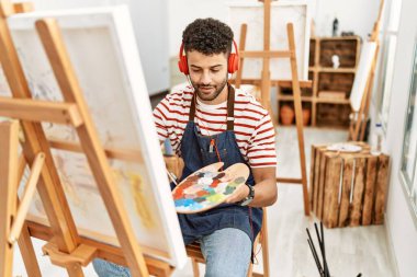Sanat stüdyosunda müzik dinleyen genç bir Arap sanatçı..