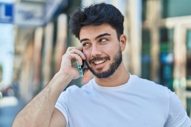 Genç İspanyol adam gülümsüyor. Kendine güveniyor. Sokakta akıllı telefondan konuşuyor.