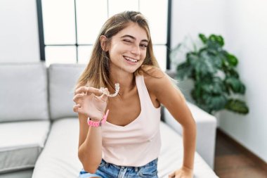 Genç sarışın bir kadın, görünmez bir hiza tutuyor, ortodontik göz kırpıyor, seksi bir ifadeyle, neşeli ve mutlu bir yüzle kameraya bakıyor.. 