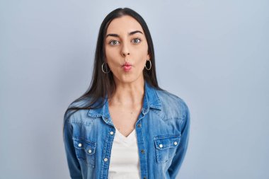 Mavi arka planda duran İspanyol kadın dudaklarıyla balık suratı yapıyor, çılgınca ve komik bir jest. Komik ifade. 