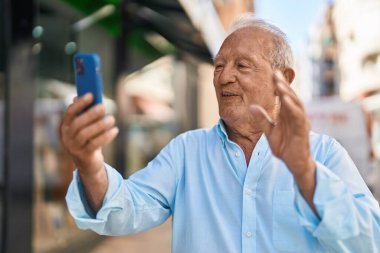 Senior grey-haired man smiling confident having video call at street
