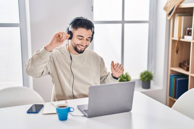 Genç Arap adam evde oturmuş müzik dinliyor.