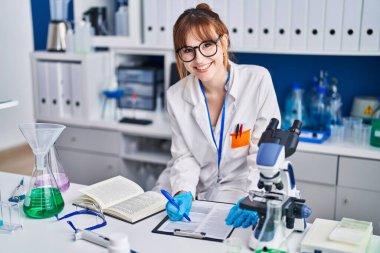 Genç kadın bilim adamı, laboratuardaki belgelere yazı yazıyor.