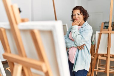 Orta yaşlı İspanyol bir kadın ciddi bir ifadeyle resim stüdyosunda resim çiziyor..