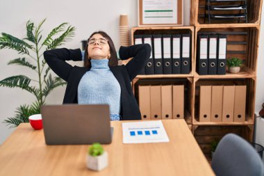 Genç ve güzel İspanyol iş kadını. Dizüstü bilgisayar kullanıyor. Ofiste elleri rahat.